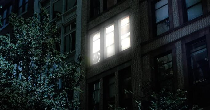 A typical New York style apartment or office building establishing shot at night with the lights from a window turning on and off. Simulated "day-for-night" composite.	