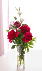 Beautiful bouquet with fragrant peonies in vase on light table