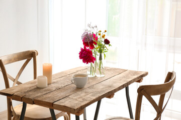 Fototapeta na wymiar Beautiful flowers in vases as floral decor on wooden table