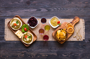 tasty and delicious bruschetta with avocado, tomatoes, cheese, herbs, chips and liquor, on a wooden background.