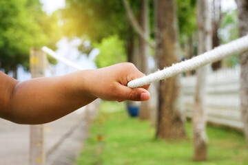 A young bay hand holding a rope at a garden.
