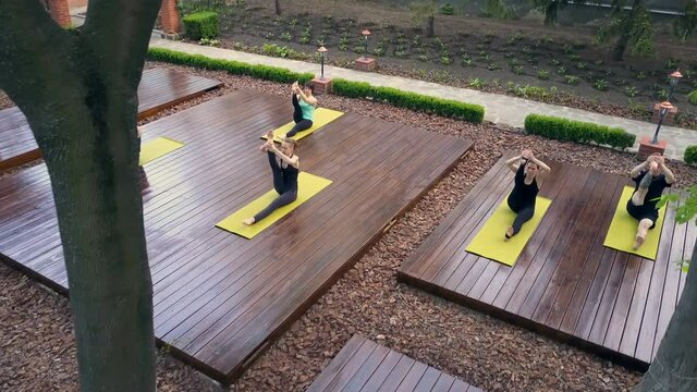Group of people sitting in the yoga pose stratching their legs drone footage