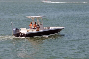 Young couple enjoying a leisurely saturday afternoon cruise on the florida intra-coastal waterway off Miami Beach in an outward engine powered blue motorboat with white trim.