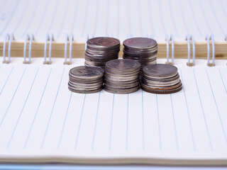 Stack of coins on a  book on a wooden desk.Concept of saving money