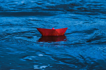Fototapeta premium Red paper boat in a stormy river