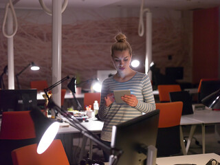 Fototapeta na wymiar woman working on digital tablet in night office