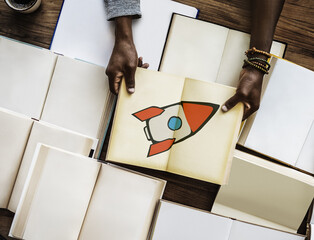 hands opening book with rocket start up icon