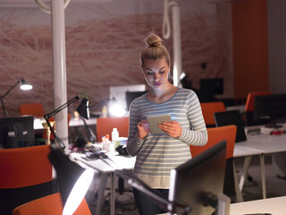 woman working on digital tablet in night office