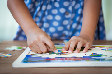 Obraz premium Child little girl hand trying to connect jigsaw puzzle piece to learn to find solution