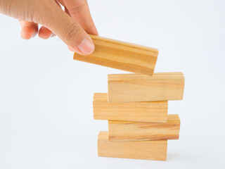 Concept of building success foundation. Women hand put wooden blocks on the stack of wooden blocks