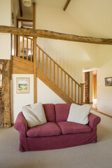 Maroon Couch by Flight of Stairs in Posh Vacation Cottage