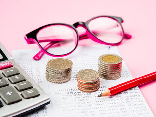 abstract money saving. financial statement with stack of coins, calculator, glasses and pencil on pink background.