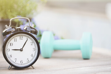 Time for exercising clock and dumbbell, sport concept