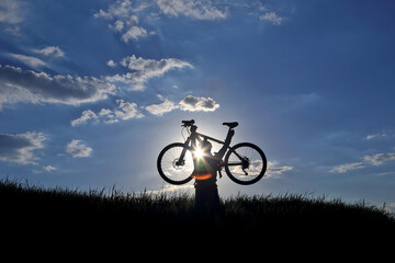 silhouette of a cyclist with a bike in the sun.