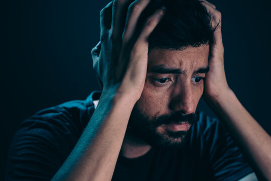 Close up of sad man in dark room. Depression and anxiety disorder concept