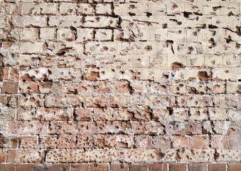 Damaged brick wall covered in holes and scars