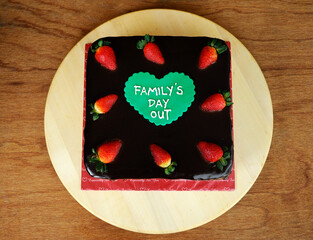 Russian black and white cake with chocolate topping and Family Day Out text on it. Half lice...