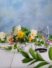 flowers and perfume bottles on a white wooden table with decorative cage on a blue pastel background