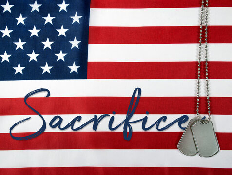 word sacrifice and military dog tags on American flag