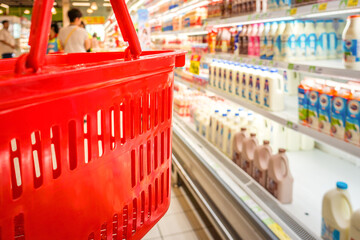 Shopping with empty red plastic basket in superstore. Customer browses the goods in food and beverage department.