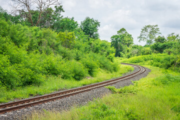Fototapeta na wymiar Curved single train track in forest of Thailand. With two parallel iron rails for movement of rail cars.