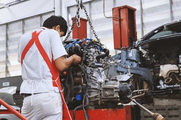 mechanic assembling an engine block of a car in the garage room service