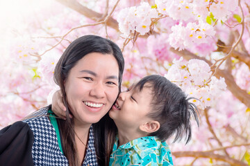 Little asian boy kissing his mother in park