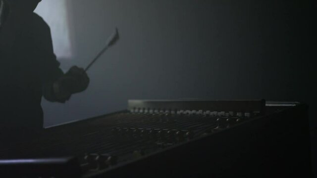 Dulcimer musical instrument. Cimbalom music player playing dulcimer sticks. Traditional string instruments. Close up of cymbal player silhouette. Dulcimer folk musician instrument