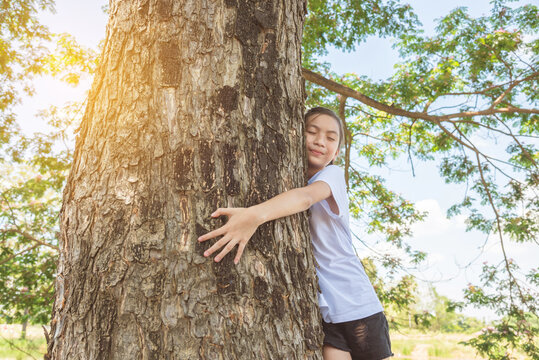 Young asian girl hugging tree trunk in park