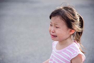 Little asian girl crying outdoors