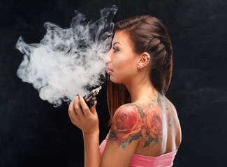 Young beautiful woman smoking ( vaping ) e-cigarette.  A cloud of vapor.