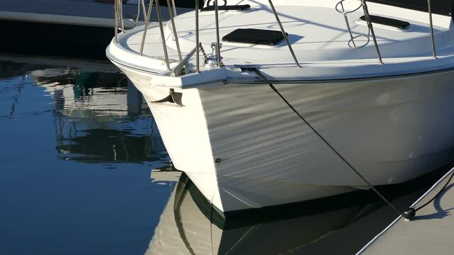 Close up of the bow of a boat with water reflections.
