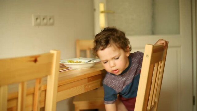 Cute little boy wearing nappy and wriggle on the chair at lunch time
