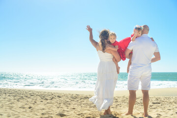 Happy family waving on the beach