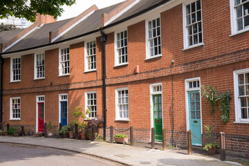 Naklejka premium Restored Victorian red brick houses with colored doors on a local road in London, UK
