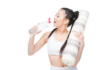 Attractive young asian woman holding yoga mat and drinking water from bottle