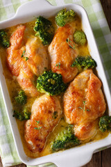 Homemade chicken breast baked with broccoli in cheese sauce close-up in dish. Vertical top view
