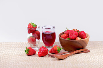Fresh strawberries and strawberry jam in the glass  jar and strawberries in a wooden bowl