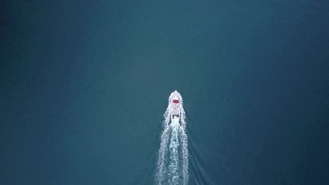 Aerial birds eye view of a ferry boat traveling in the blue Pacific ocean. Leaves a wake behind it. smooth glassy water.