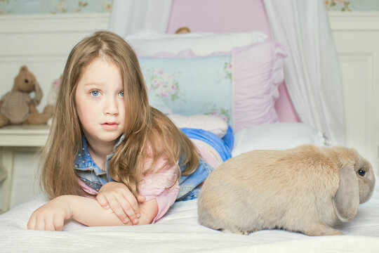 girl with pet rabbit lying on the bed. the concept of Allergy