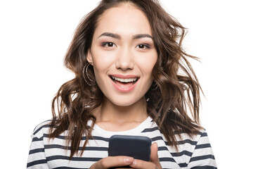 cheerful woman with smartphone in hands looking at camera isolated on white