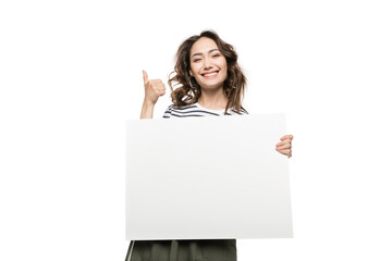 Smiling young woman holding blank white card and showing thumb up