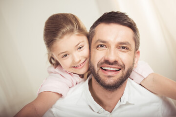Close-up portrait of happy father and daughter hugging and smiling at camera