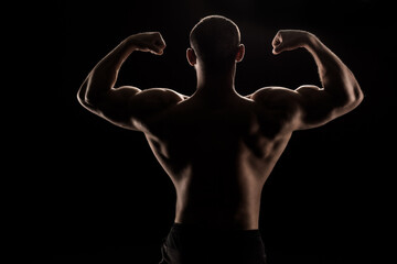 Fototapeta na wymiar back view of young shirtless athlete flexing biceps