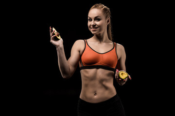 smiling sporty girl holding avocado isolated on black