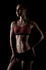 Fototapeta na wymiar muscular sportswoman posing in sportswear and showing her slim body isolated on black