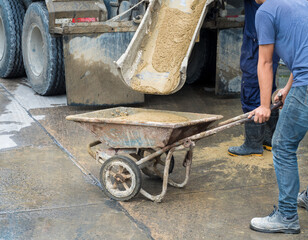 Controlled Low Strength Material (CLSM) pouring down from mixer truck to a trolley and workers...