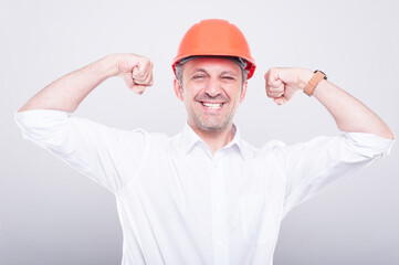 Portrait of architect wearing hardhat posing showing biceps