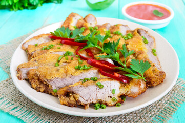 Golden schnitzel chopped slices and a bowl of vegetable salad on a light wooden background. Healthy diet.