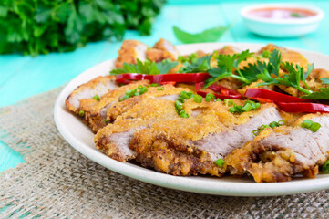 Golden schnitzel chopped slices and a bowl of vegetable salad on a light wooden background. Healthy...
